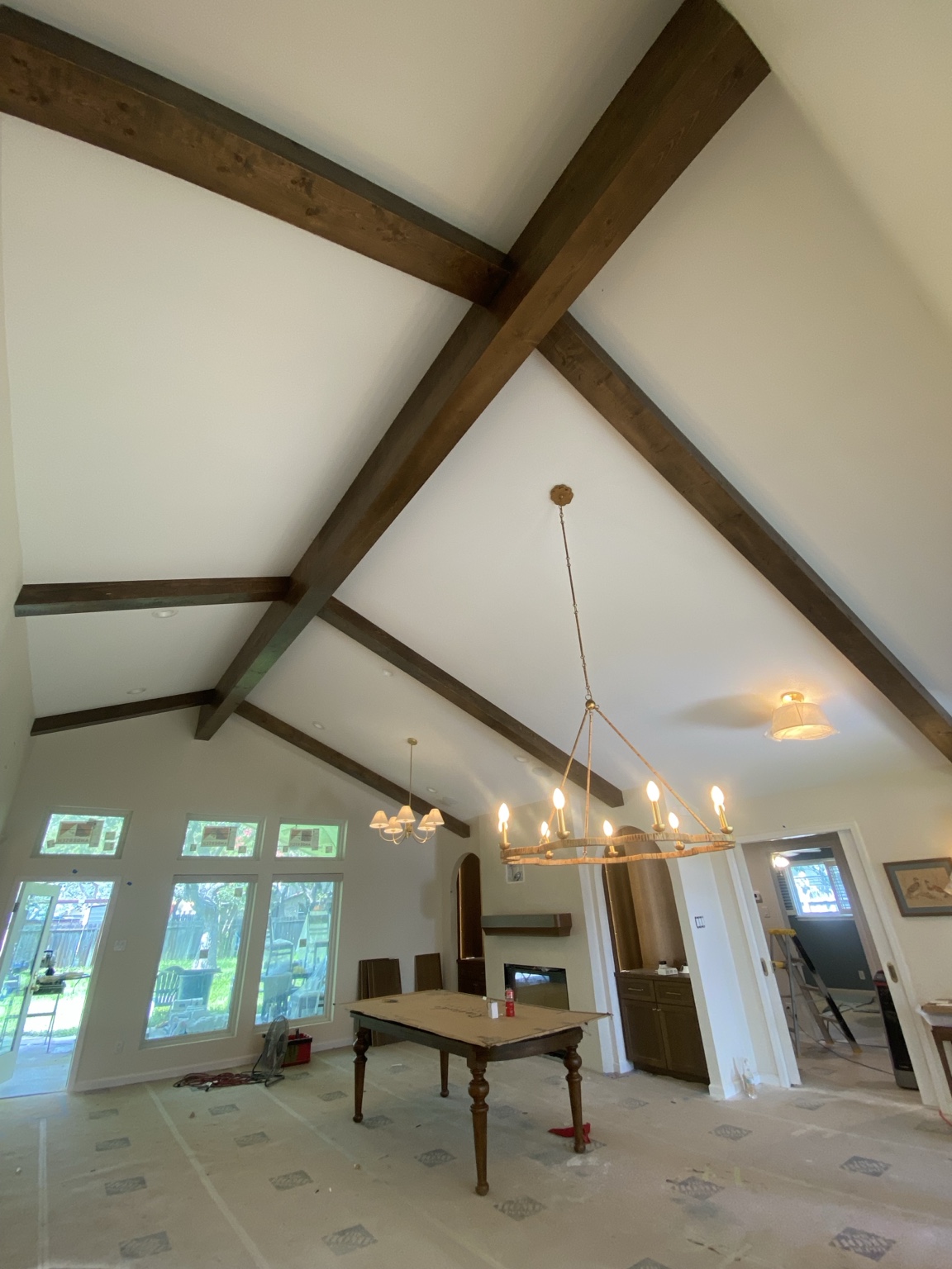Stained wood ceiling beams installed across a vaulted great room during construction